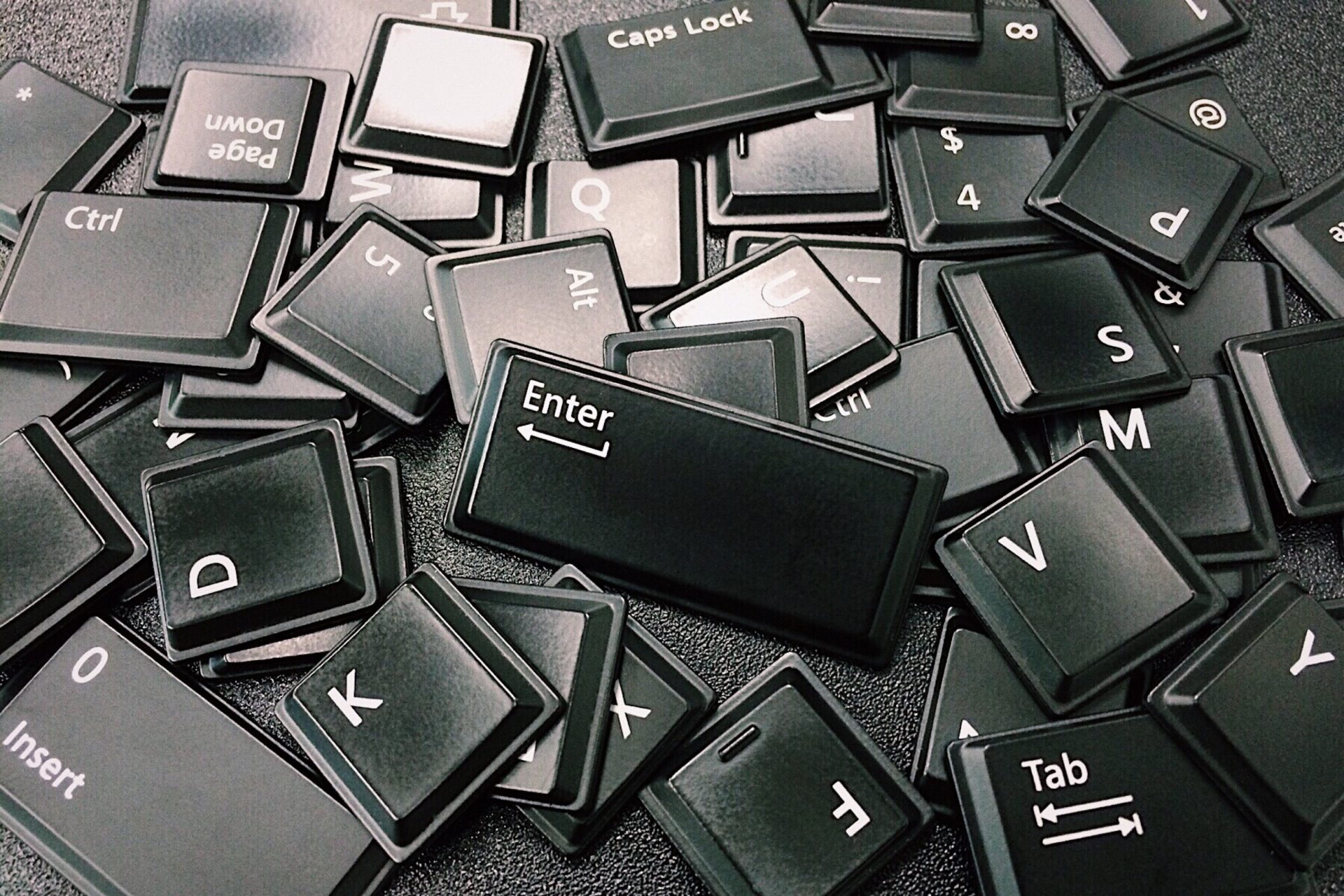 A black and white photo of a jumbled pile of keyboard keys