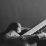 a black and white shot of hands grasping a mobile phone