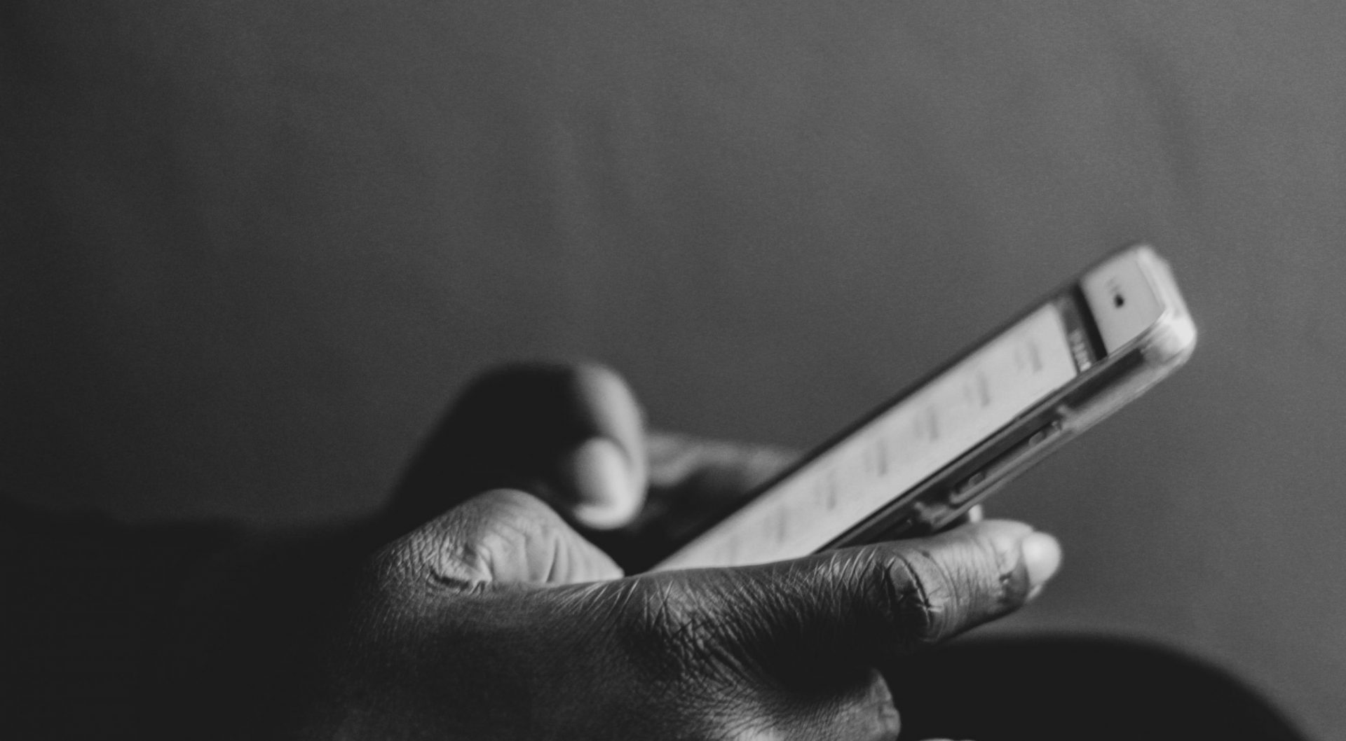 a black and white shot of hands grasping a mobile phone