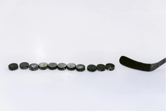 hockey pucks lined up on the ice with a hockey stick ready to shoot